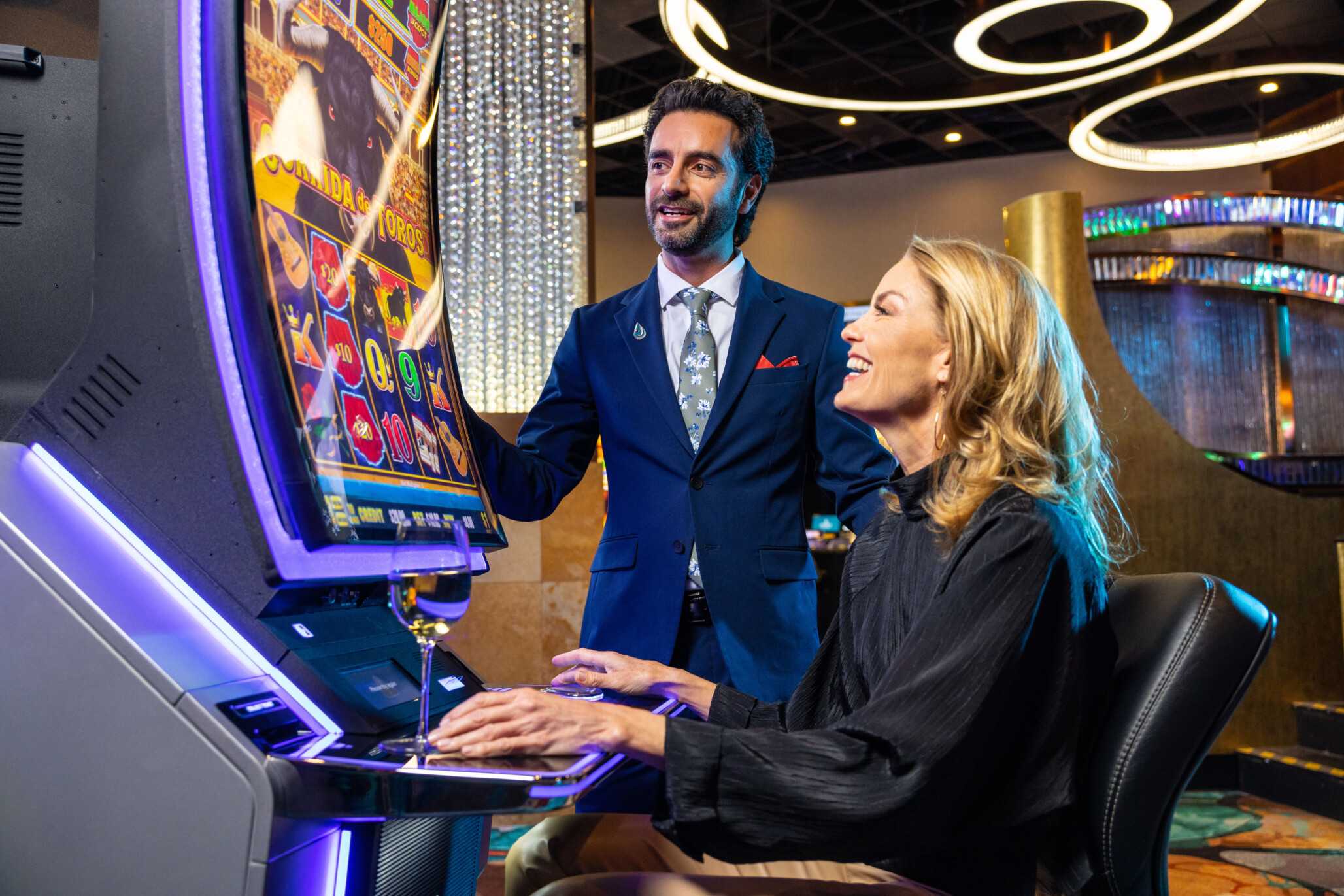 A casino host is encouraging a slot player.
