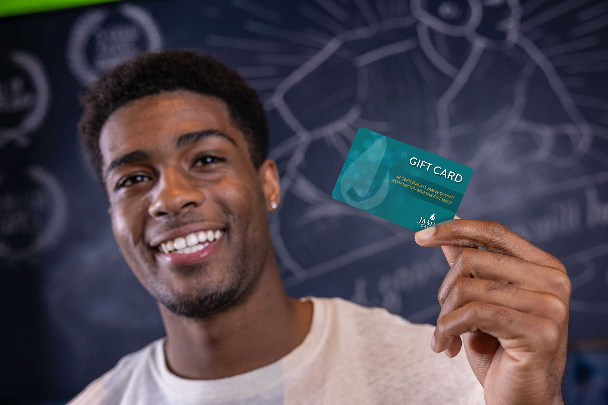 A young man smiling and holding up the Jamul Casino gift card.